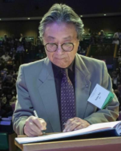 Victor Nee signs academy book of members in front of auditorium audience 